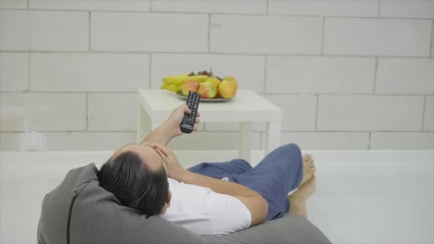 Hombre viendo la televisión verde en la habitación y comiendo una manzana — Vídeo de stock