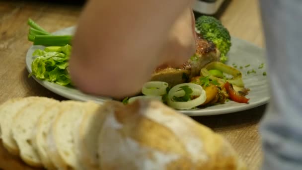 Mulher coloca um bife de carne e legumes em um prato — Vídeo de Stock