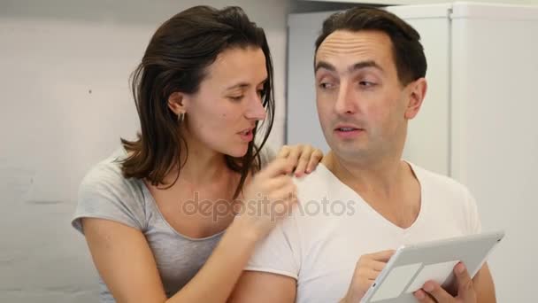 Casal feliz usa tablet enquanto sentado na mesa da cozinha — Vídeo de Stock