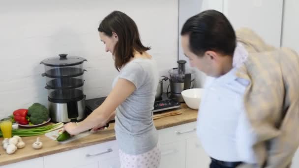 Любящий парень обнимает свою улыбающуюся подружку на кухне рано утром с приготовленным завтраком — стоковое видео