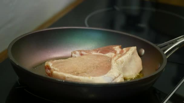 Deliziosa bistecca posta sulla griglia calda guarnita con sale e pepe. Carne cruda di manzo fritta. carne essendo burro fritto e scaldandosi in una pentola. primo piano. rallentatore — Video Stock