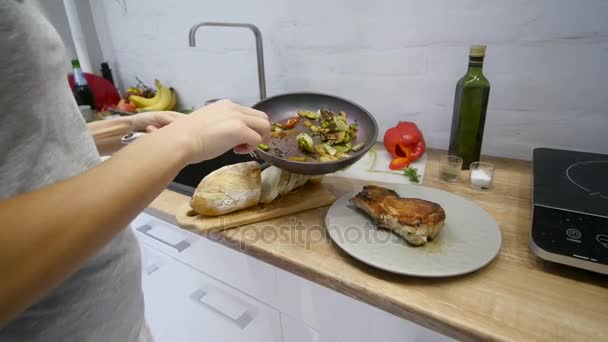 Vrouw zet een biefstuk van vlees en groenten op een plaat — Stockvideo