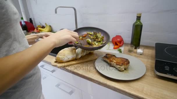 Kvinnan sätter en kött-biff och grönsaker på en tallrik — Stockvideo