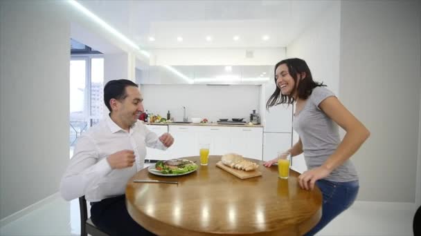 Casal feliz conversando e tomando café da manhã juntos em casa na cozinha — Vídeo de Stock