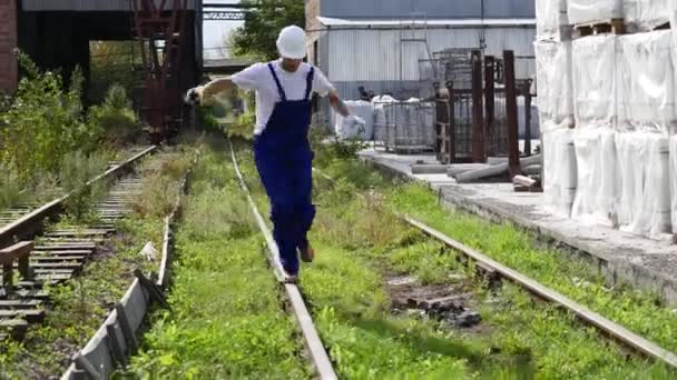 Spoorweg werknemer in wit helm wandelen langs de spoorweg — Stockvideo