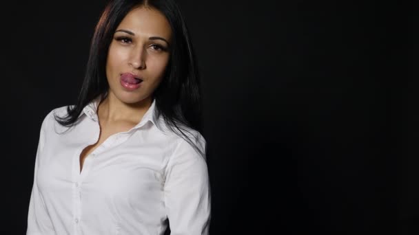 Jonge sexy vrouw likken haar lippen. op donkere achtergrond — Stockvideo