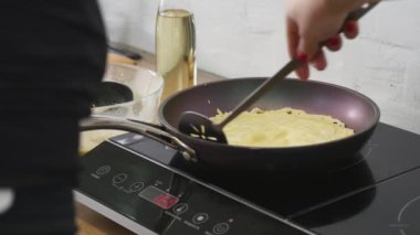 Bir tavada pişirme krep. Bir tavada pişirme krep. Kadın krep tavada çevirir. Mutfak Sanatları. Pişirme