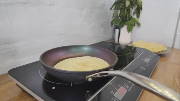 Pfannkuchen in einer Pfanne kochen. Pfannkuchen in einer Pfanne zubereiten. die Frau dreht den Pfannkuchen in der Pfanne. Kochkunst. Kochen — Stockvideo