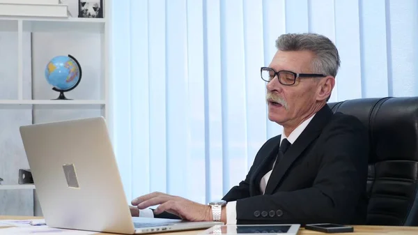 elderly businessman working with computer in modern office