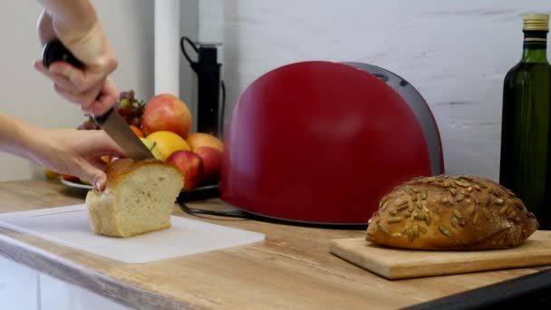 Eine Frau schneidet mit einem Brotmesser einen Laib Brot — Stockvideo