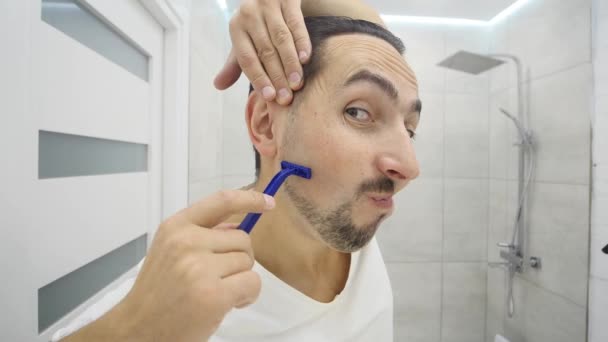Человек бреется перед зеркалом — стоковое видео