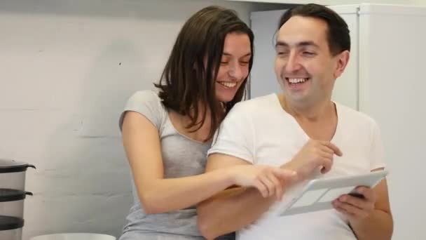 Casal feliz usa tablet enquanto sentado na mesa da cozinha — Vídeo de Stock