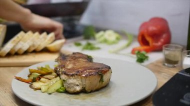 Kadın eti biftek ve sebze bir tabağına koyuyor