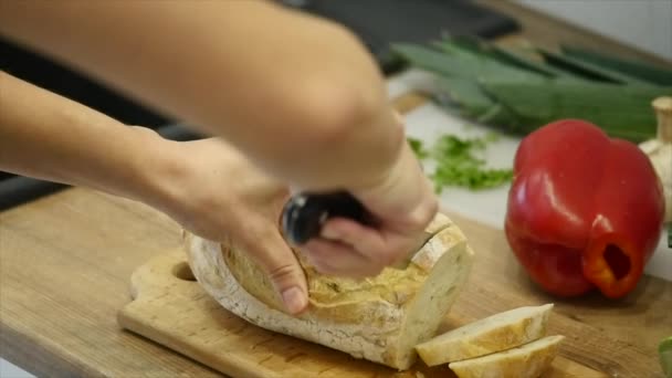 Eine Frau schneidet mit einem Brotmesser einen Laib Brot. Zeitlupe — Stockvideo