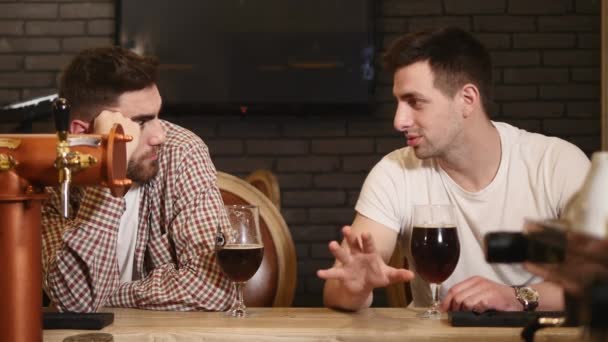 Dwóch młodych mężczyzn przyjaciół siedzi barze i rozmawiać ze sobą podczas picia piwa — Wideo stockowe