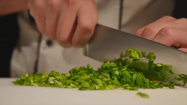 Couper les oignons verts avec un couteau sur la planche. Coupe verte sans les mains dans le cadre. Chef coupe les ingrédients pour la soupe. De la verdure tranchée. Cuisiner de la nourriture. Hacher les ingrédients de la salade — Video