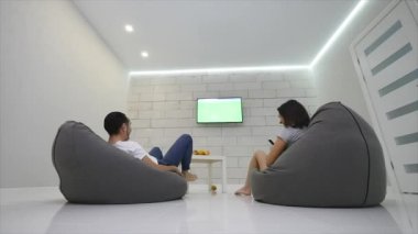 Çift ana sayfa izlerken televizyon koltuğu çantada. Çift yeşil ekranlı televizyon izleyen