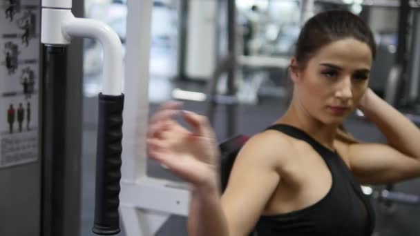 Женщина тренирует руки и плечи на тренажере в спортзале — стоковое видео