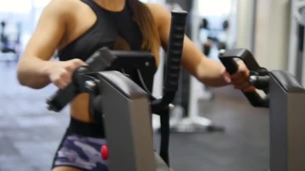 Mujer entrena brazos y hombros en simulador en gimnasio — Vídeos de Stock