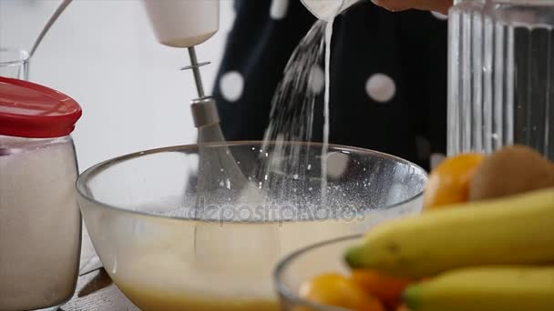 Giovane donna prepara impasto mescolando ingredienti nella ciotola utilizzando frusta in cucina. Cibo fatto in casa. Colpo di rallentamento — Video Stock