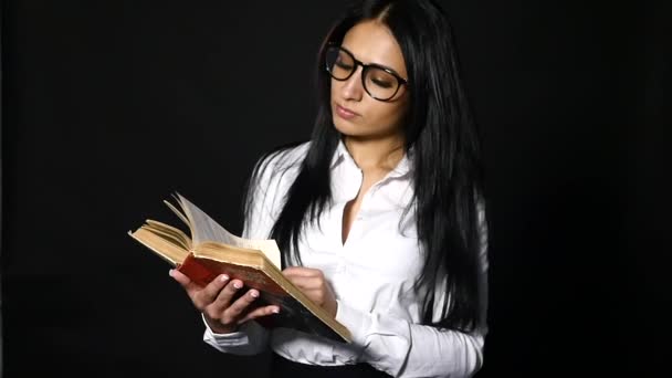 Retrato atractiva mujer leyendo libro. hermosa joven morena con el pelo largo con camisa blanca posando en el estudio — Vídeo de stock