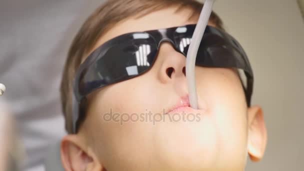 Дитячий пацієнт сидить на стоматологічному стільці в дитячому кабінеті стоматологів — стокове відео
