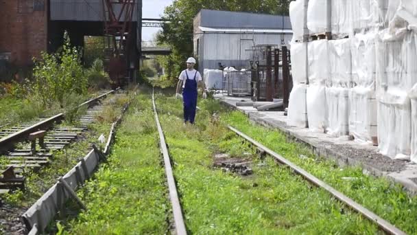 Trabajador ferroviario en casco blanco caminando a lo largo del ferrocarril — Vídeos de Stock