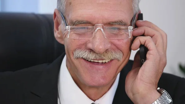 Senior man speaks with white smartphone in office. close up — Stock Photo, Image