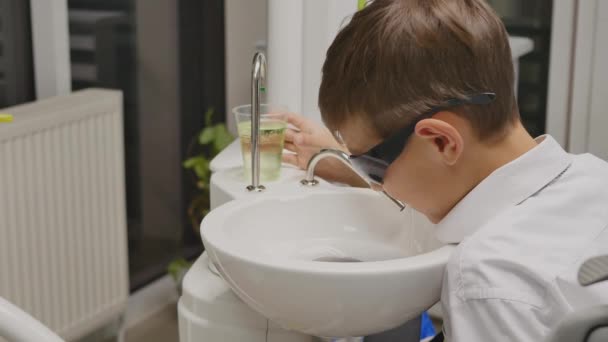 Kinderpatient sitzt auf Zahnarztstuhl in Kinderzahnarztpraxis — Stockvideo