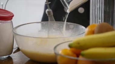 Genç bayan, mutfaktaki çırpı çırpıcısını kullanarak hamuru kaseye karıştırıyor. Ev yapımı yemek. Yavaş çekim.