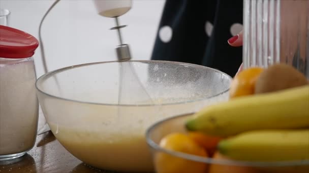 Giovane donna prepara impasto mescolando ingredienti nella ciotola utilizzando frusta in cucina. Cibo fatto in casa. Colpo di rallentamento — Video Stock