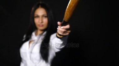 Vahşice kameraya bakarak, yarasa siyah arka plan üzerinde tutan genç güzel kız. ağır çekim. seçici odak