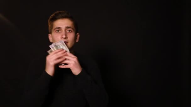 Деловой парень бросает деньги на черный фон — стоковое видео