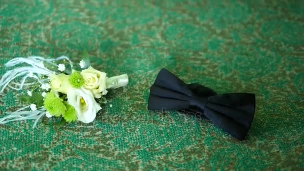 A black bow tie and pretty boutonniere on a green background — Stock Video