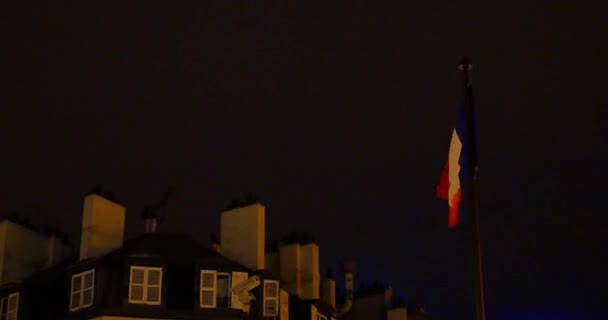 Bandeira francesa acenando ao vento perto de casa no fundo do céu noturno — Vídeo de Stock