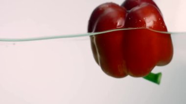 Stüdyo su sıçrama içinde akvaryum beyaz zemin üzerine kırmızı biber vurulmuş
