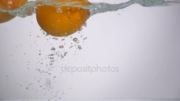Два свежих апельсина падают в воду — стоковое видео