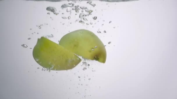Metade da maçã cai na água no fundo branco — Vídeo de Stock
