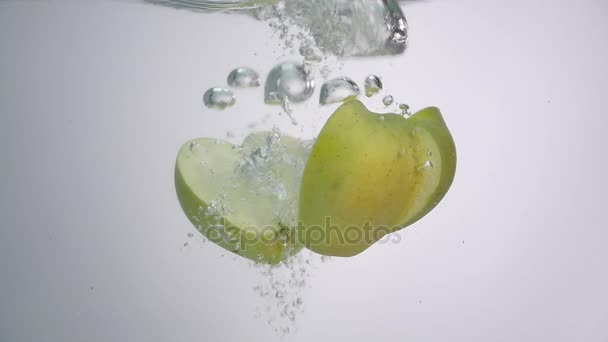Μισό μήλο πέφτει στο νερό σε λευκό φόντο — Αρχείο Βίντεο