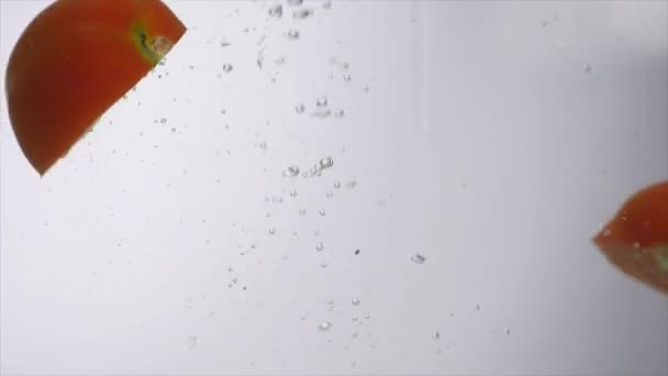 tomates tranchées tombant dans l'eau sur fond blanc 