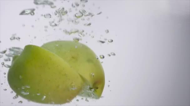 La mitad de la manzana cae en el agua sobre fondo blanco — Vídeos de Stock