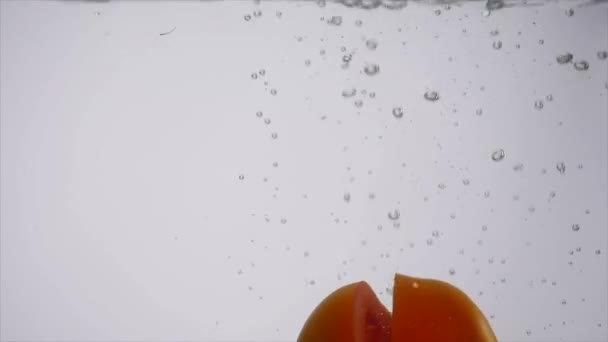 白い背景の水に陥るトマトをスライス — ストック動画