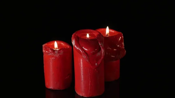 Закройте 3 зажженных красных свечи, вращающихся вокруг черного фона — стоковое фото