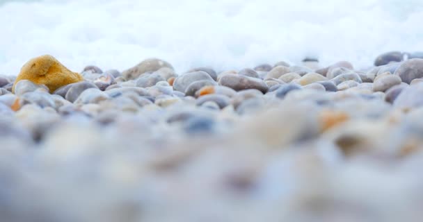 Хвиля покриває кам'яний пляж моря, крупним планом, жовтий камінь — стокове відео