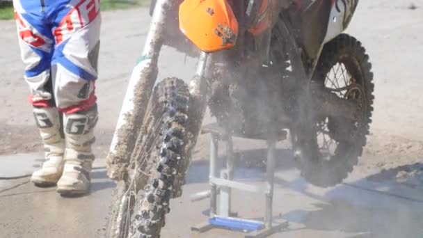 Mann wäscht Rennrad nach dem Wettkampf im Motocross