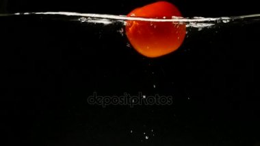 Siyah arka plan üzerine düşen suya domates