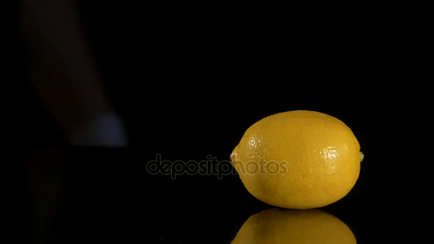 Nahaufnahme eines Mannes, der Zitrone auf schwarzem Stein schneidet — Stockvideo