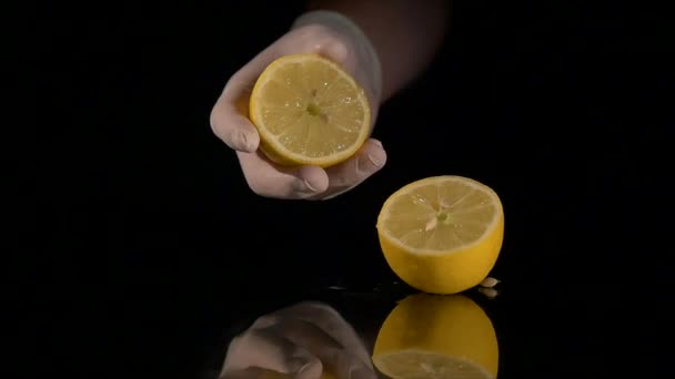 Hand squeezing lemon on dark background — Stock Video