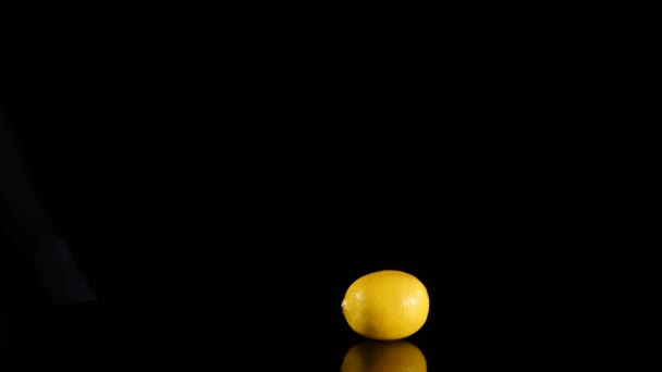 Nahaufnahme eines Mannes, der Zitrone auf schwarzem Stein schneidet — Stockvideo