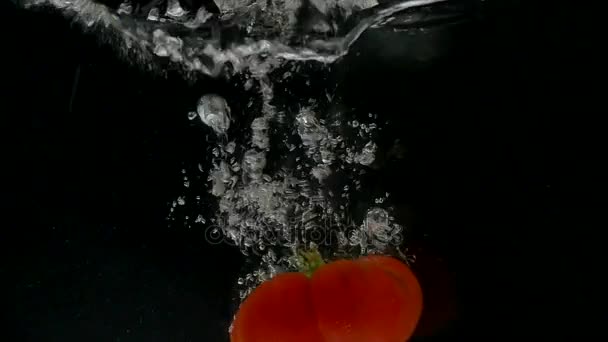 在黑色背景上掉进水里的西红柿 — 图库视频影像